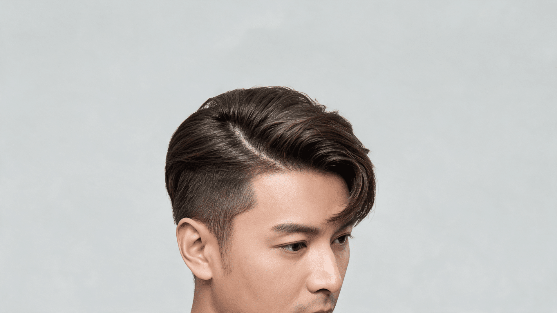Man with comb over hairstyle, hair neatly swept to one side with a natural finish and soft volume.