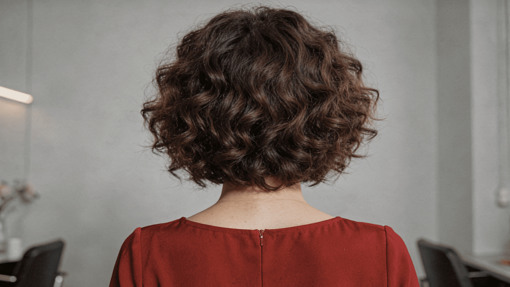 Rounded curly haircut with full sides and a slightly flatter top