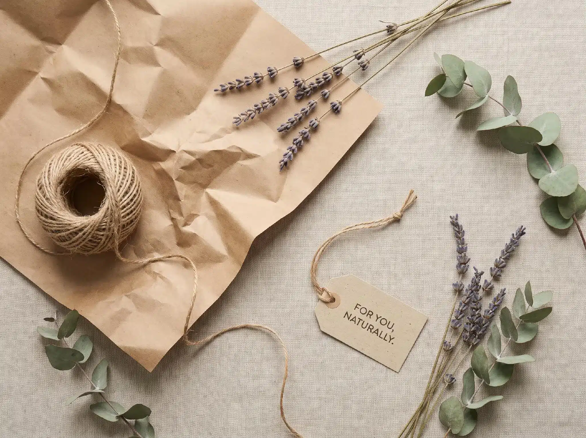Brown kraft paper with twine, lavender sprigs, and eucalyptus on linen surface
