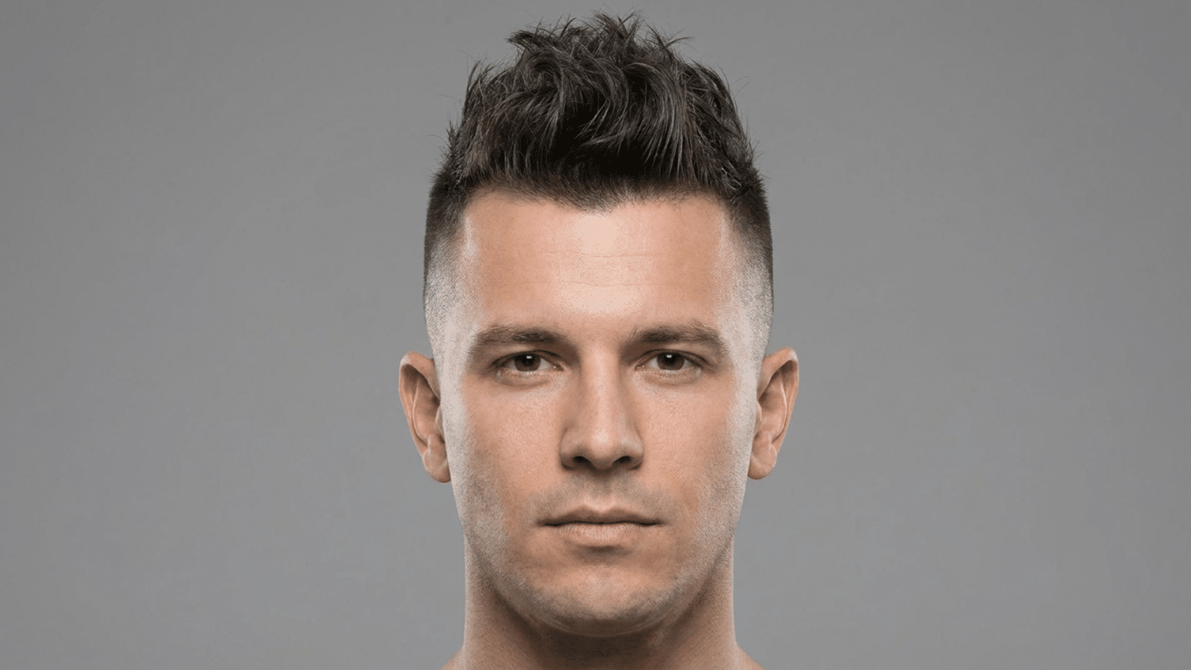 Faux hawk hairstyle for men with thinning hair showing lifted textured center strip from front to crown with close-cropped sides, front view.