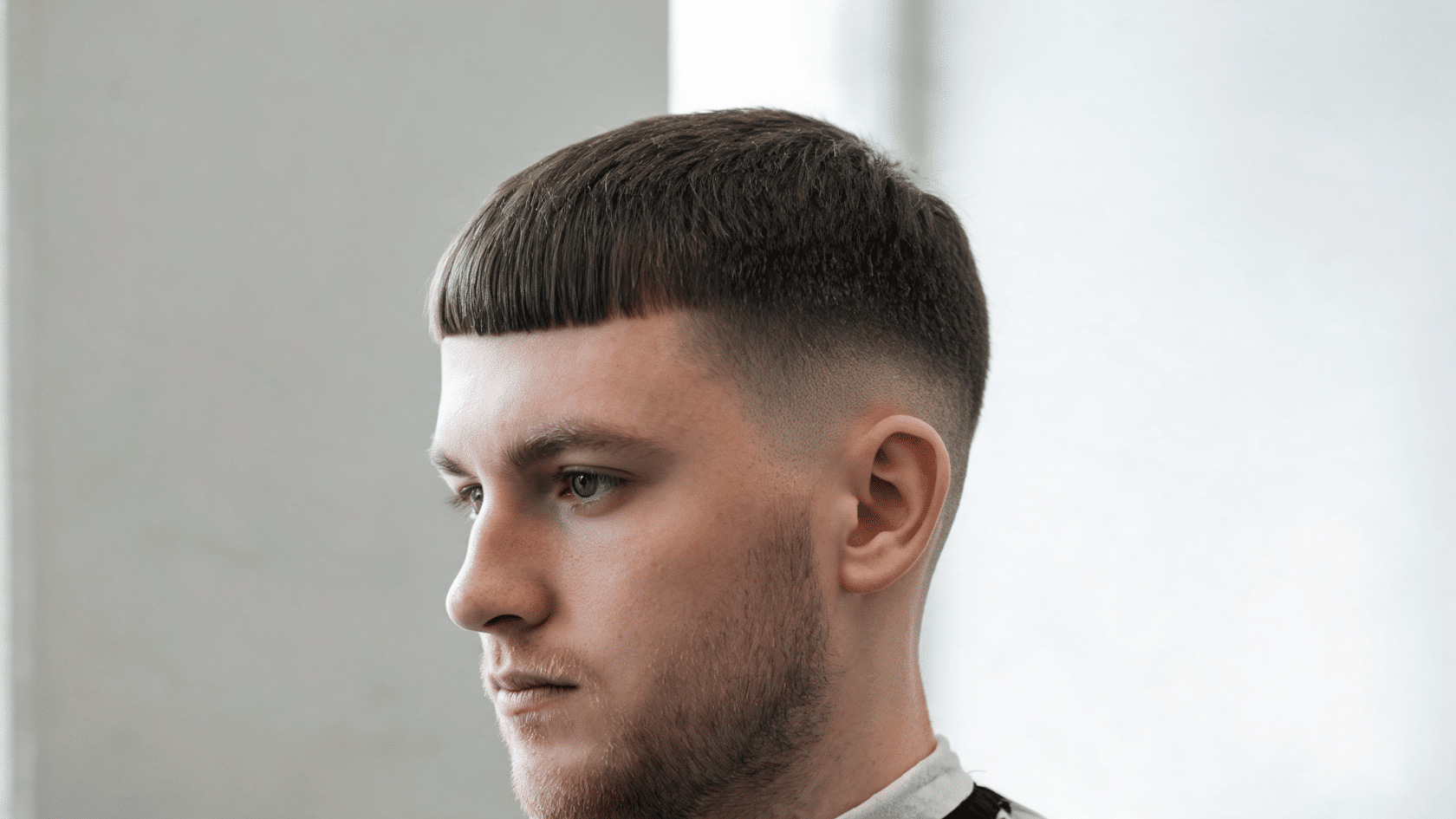 Man with a French crop haircut, blunt fringe, and short faded sides.