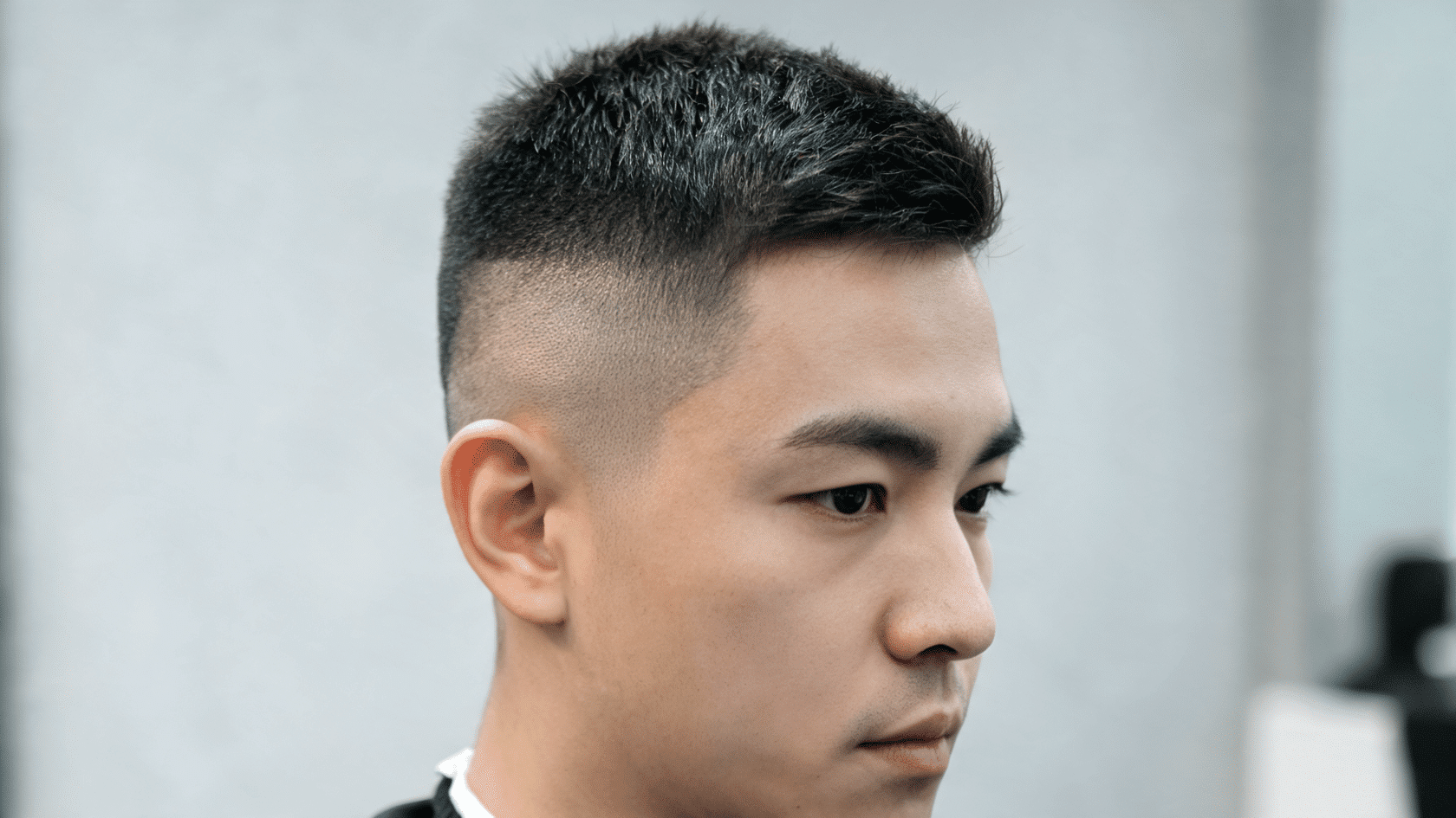 Man with a high and tight haircut, short textured top, and closely faded sides.