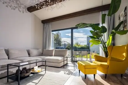Bright living room with beige sectional sofa, yellow armchair, and large potted plant by window
