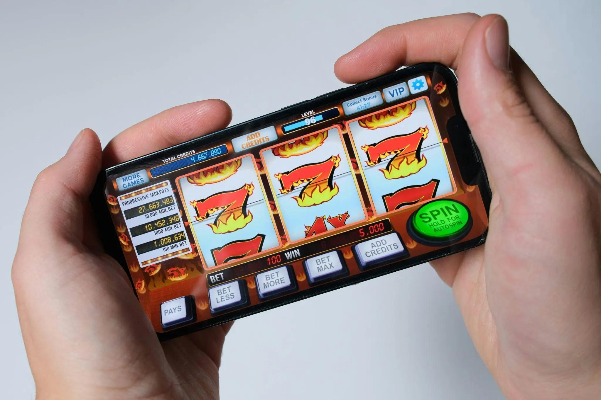 Hands holding a smartphone displaying a digital slot machine game with flame graphics