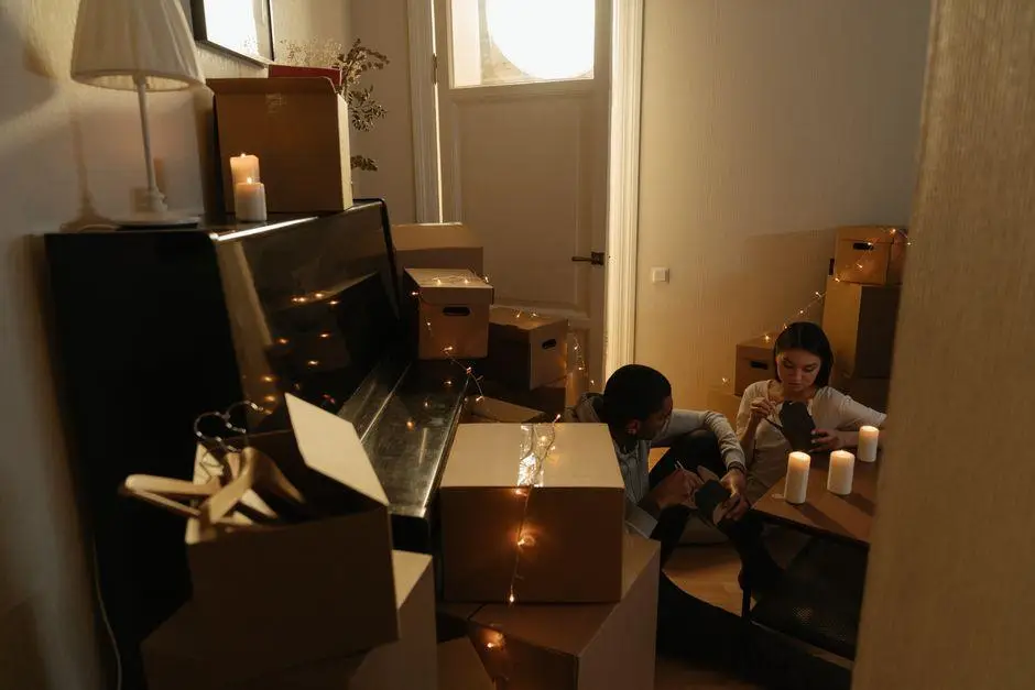 Couple sitting among moving boxes and candles in dimly lit room