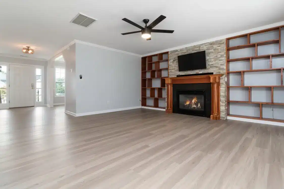 Spacious living room with wooden flooring, stone fireplace, and built-in shelving units