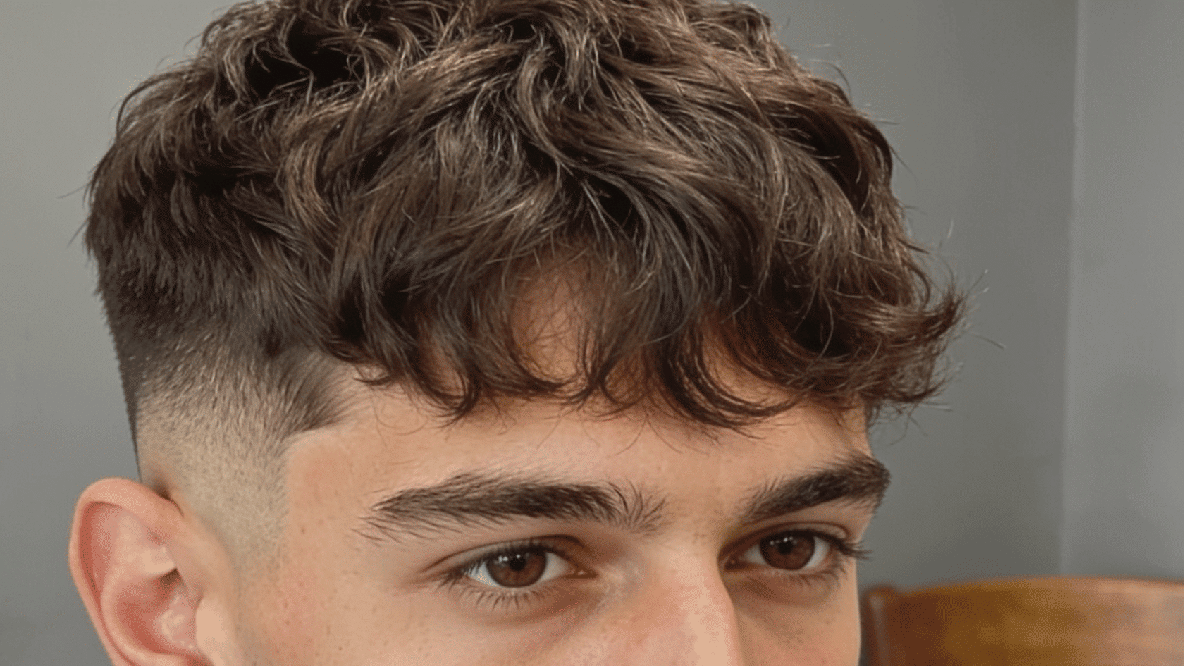 Low fade haircut with a gradual taper above the ears and a textured top