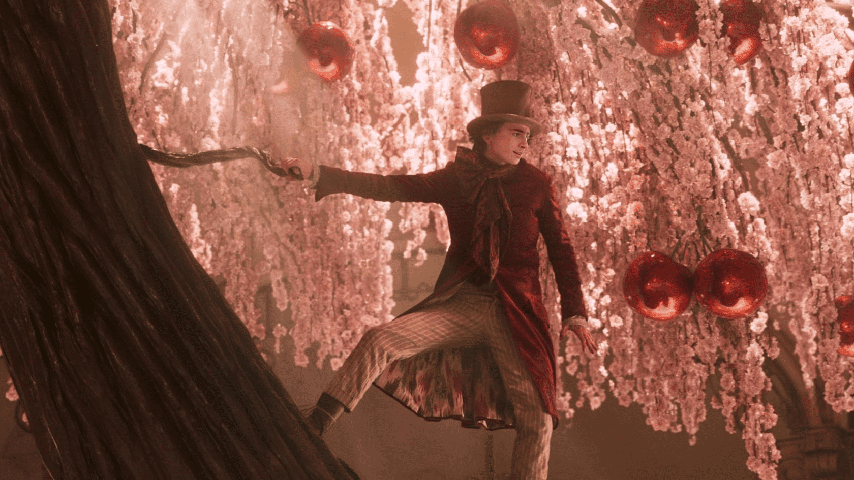 Man in top hat and burgundy coat stepping on tree branch amid cherry blossoms and red ornaments