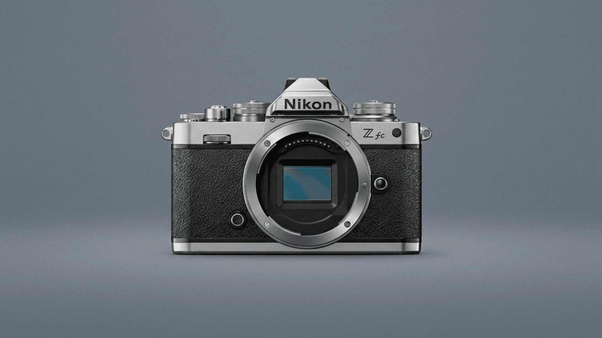 Nikon Z fc mirrorless camera body with exposed lens mount on a blue-gray background.