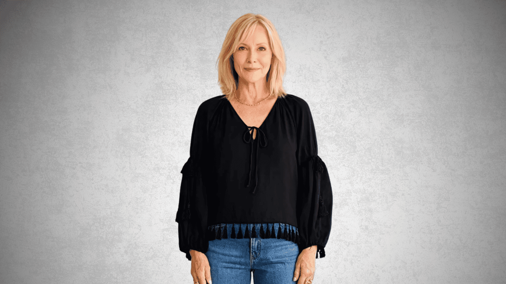 Older woman wearing a black boho blouse with tassel details and jeans