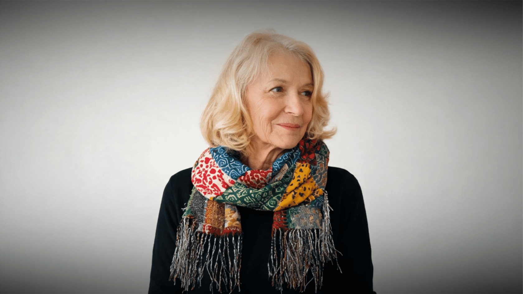 Older woman wearing a colorful patterned boho scarf with black top