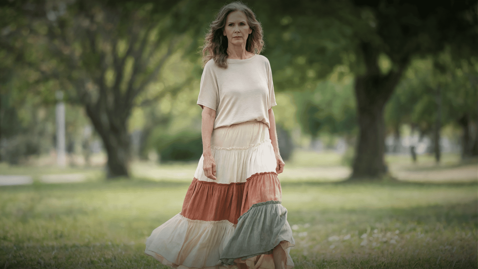 Older woman wearing a layered boho skirt and cream top in a park