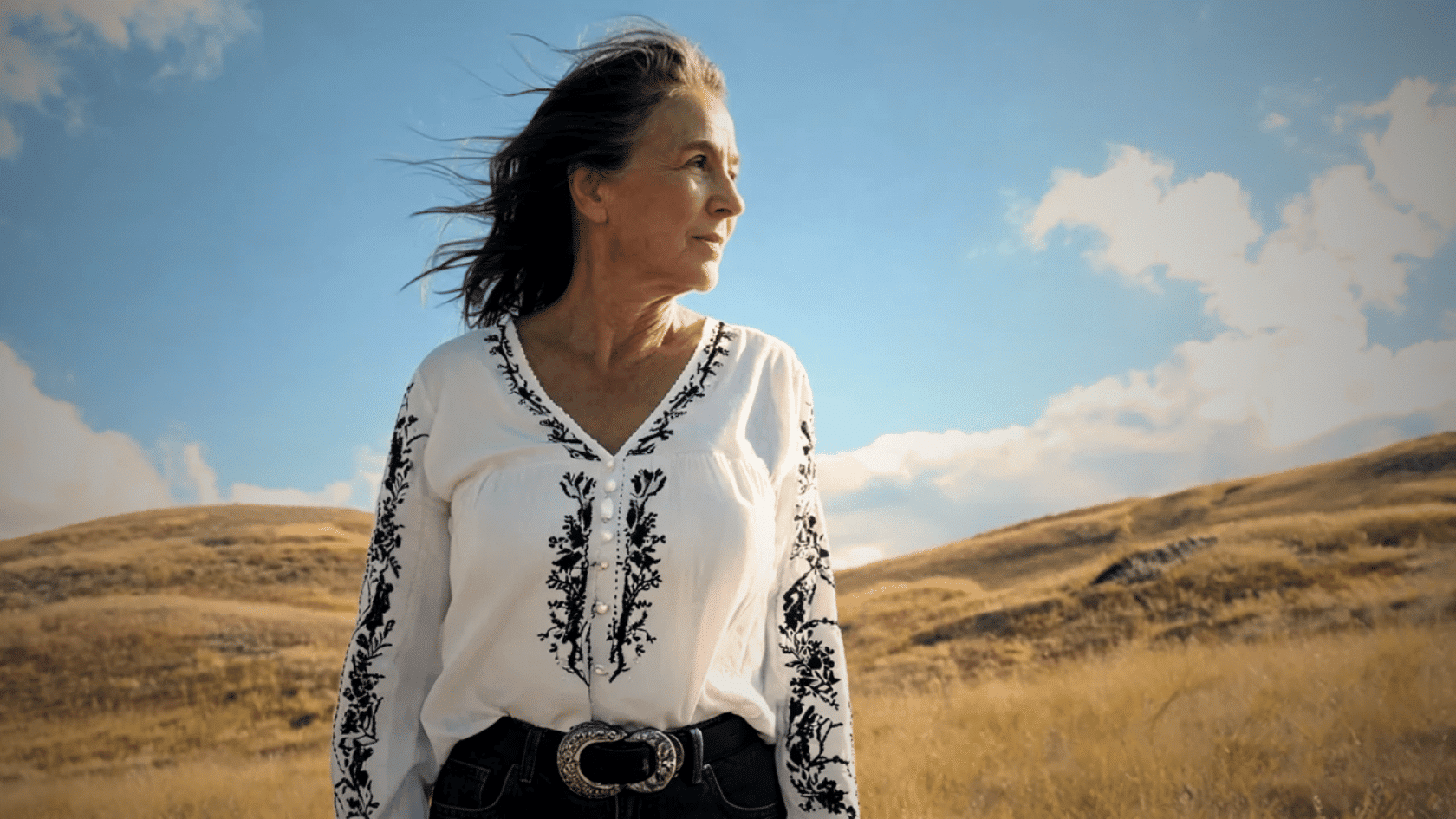 Older woman wearing a white embroidered boho blouse outdoors in a field
