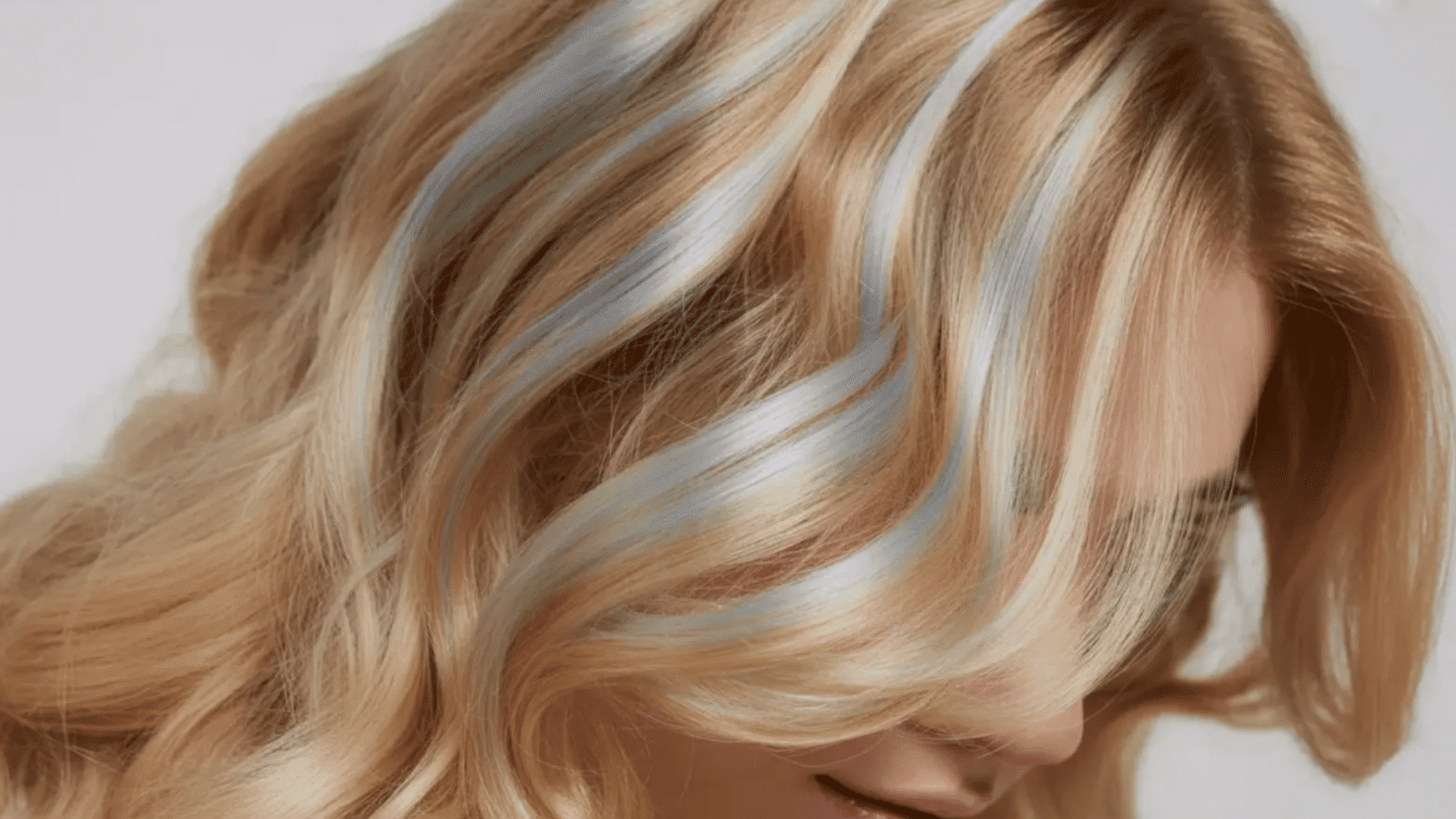Blonde hair with light blue and silver highlights styled in loose waves.