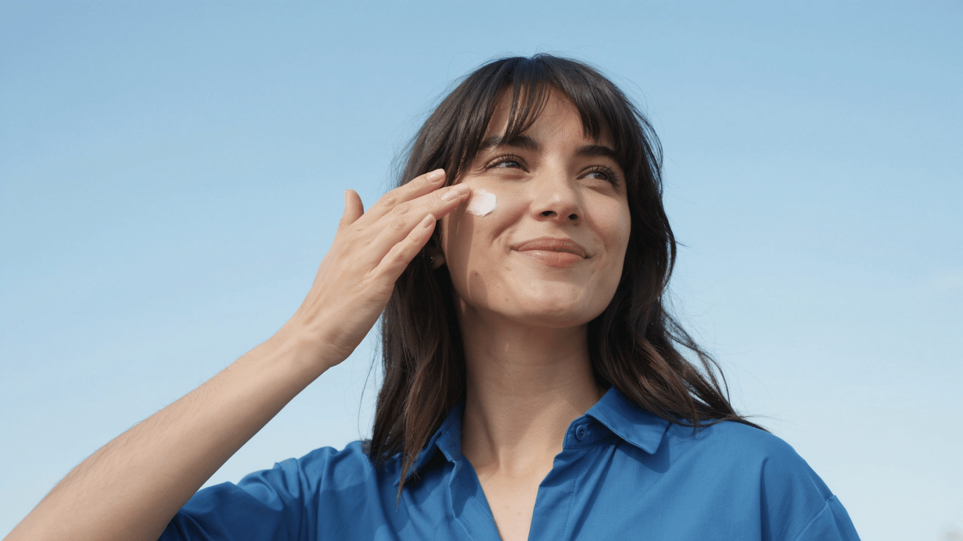 Person applying sunscreen outdoors for daily skin protection