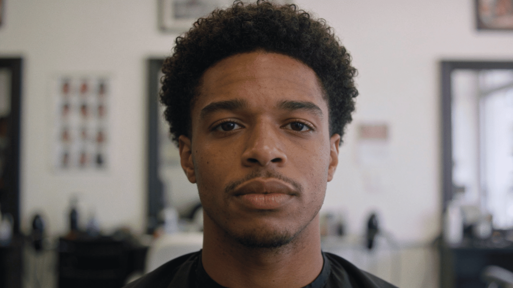 Short curly afro haircut with tight curls and clean barbershop background
