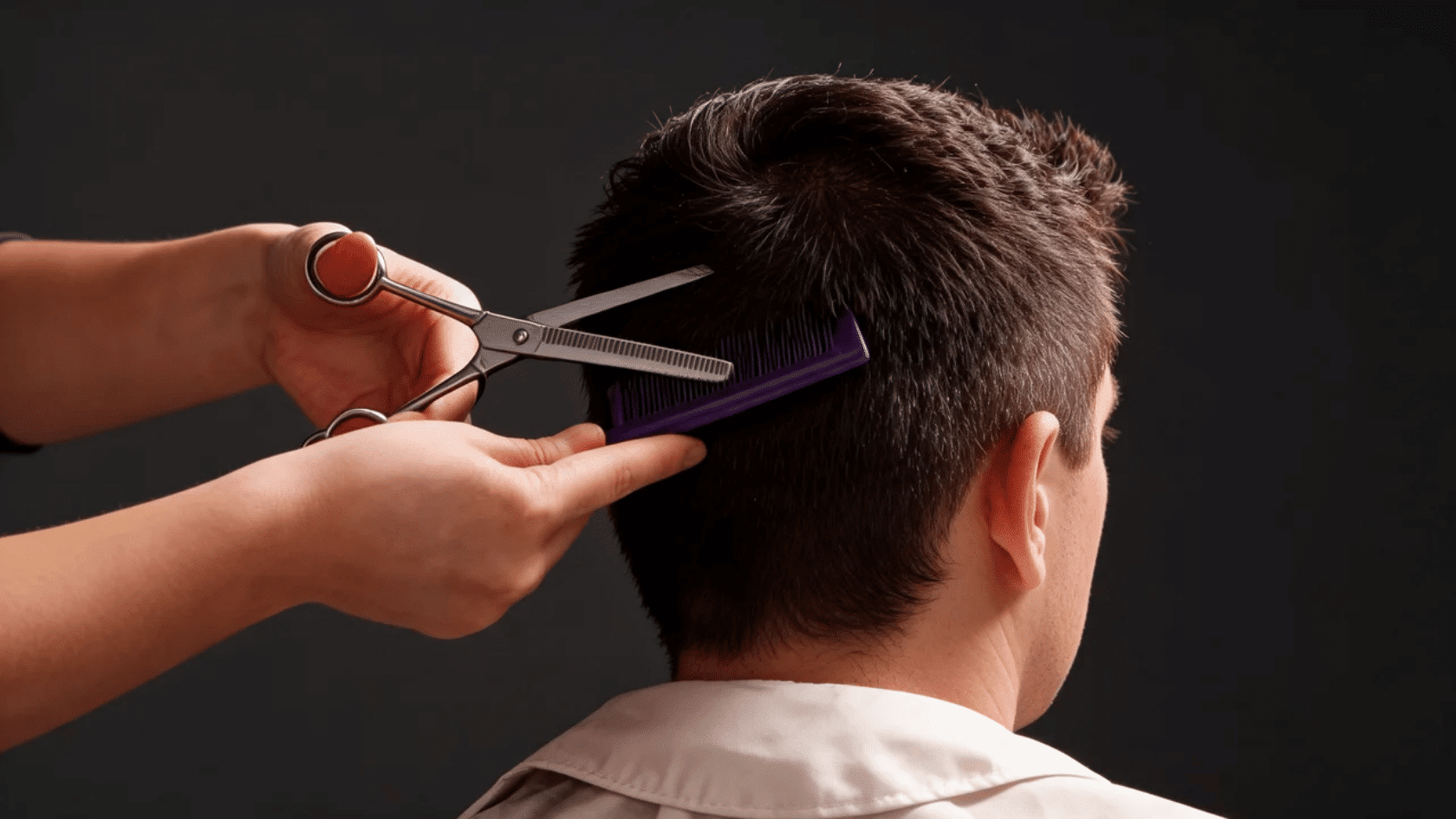 Short haircut being trimmed with scissors and a comb in a salon.