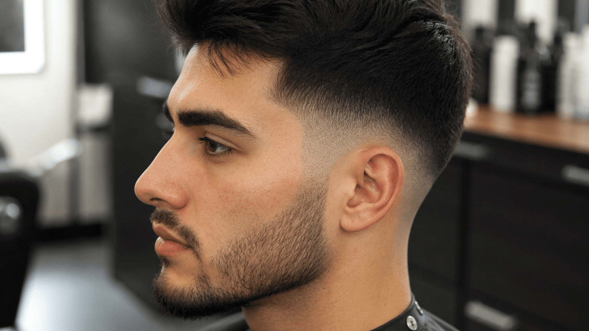 Side profile of a man showing a clean skin fade haircut with textured hair on top and smooth blending around the sides.