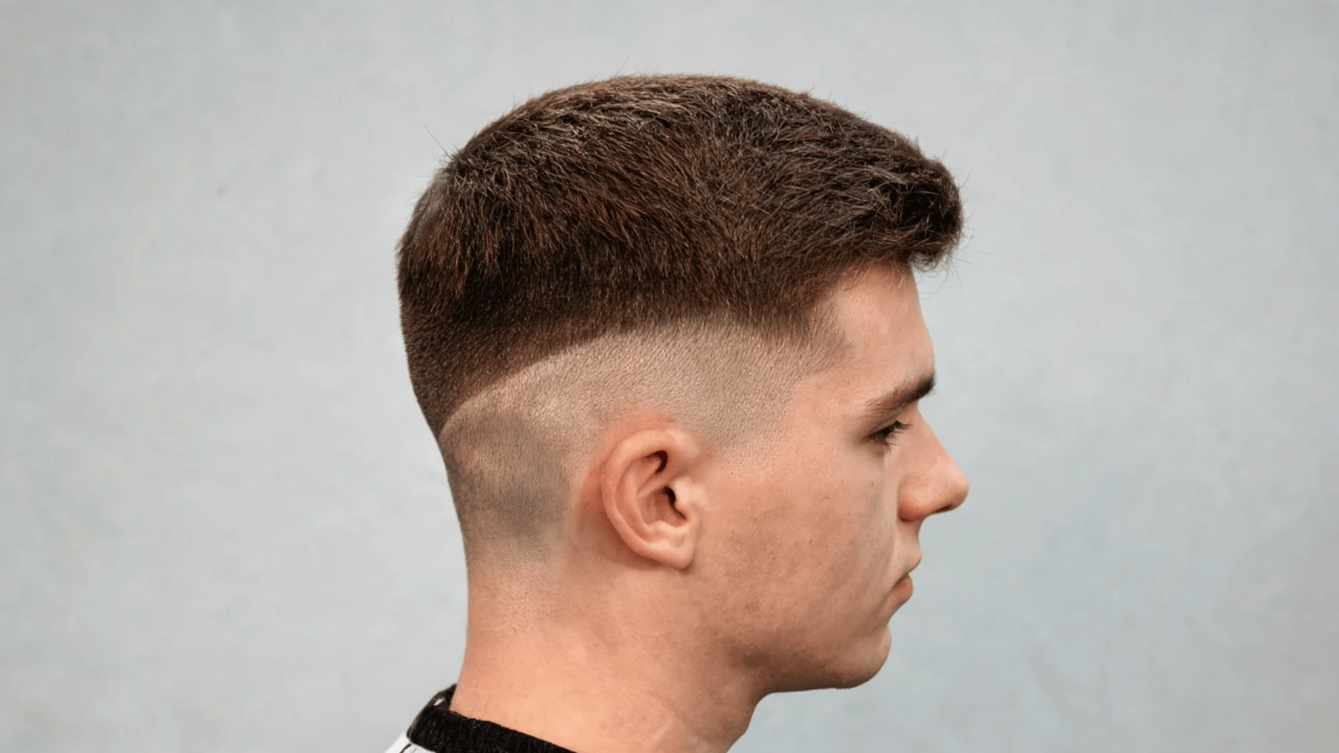 Side profile of a man showing a high bald fade haircut with a sharp skin fade and strong contrast on the sides.