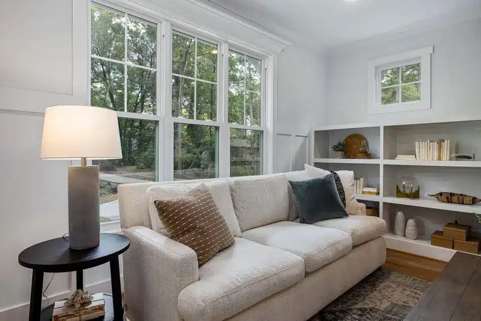 Cozy living room with beige sofa, patterned pillows, and built-in bookshelves by large window