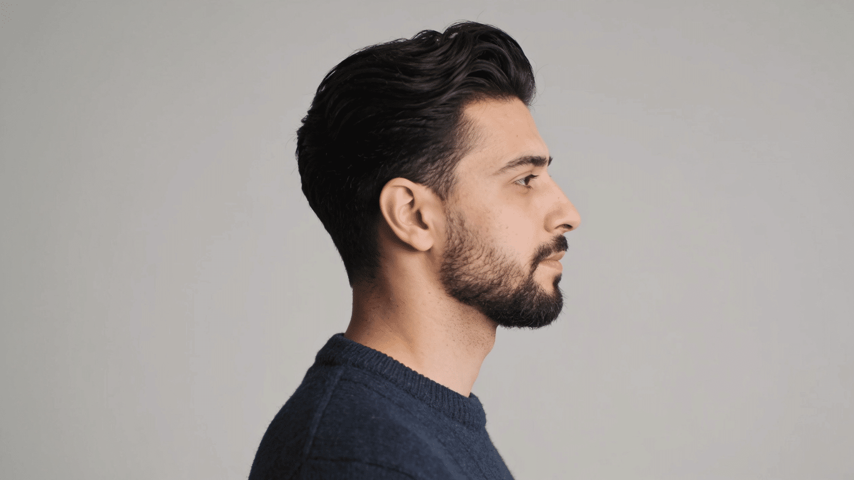 Man with a slick back haircut and full beard shown in side profile.