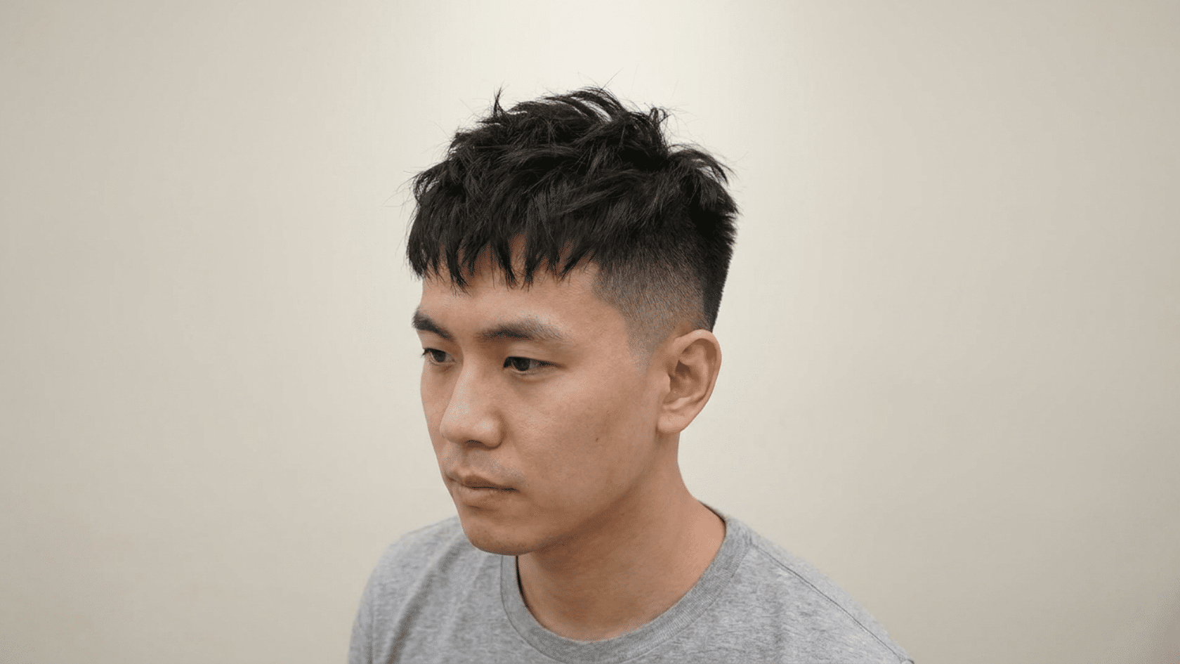 Textured crop hairstyle for men with thinning hair showing choppy lifted layers at the crown with tight fade on sides, three-quarter view.