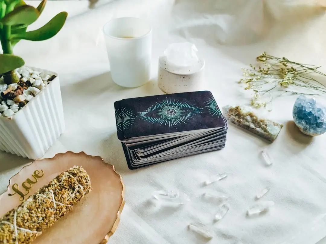 Tarot cards stack with crystals and potted plant on white fabric surface