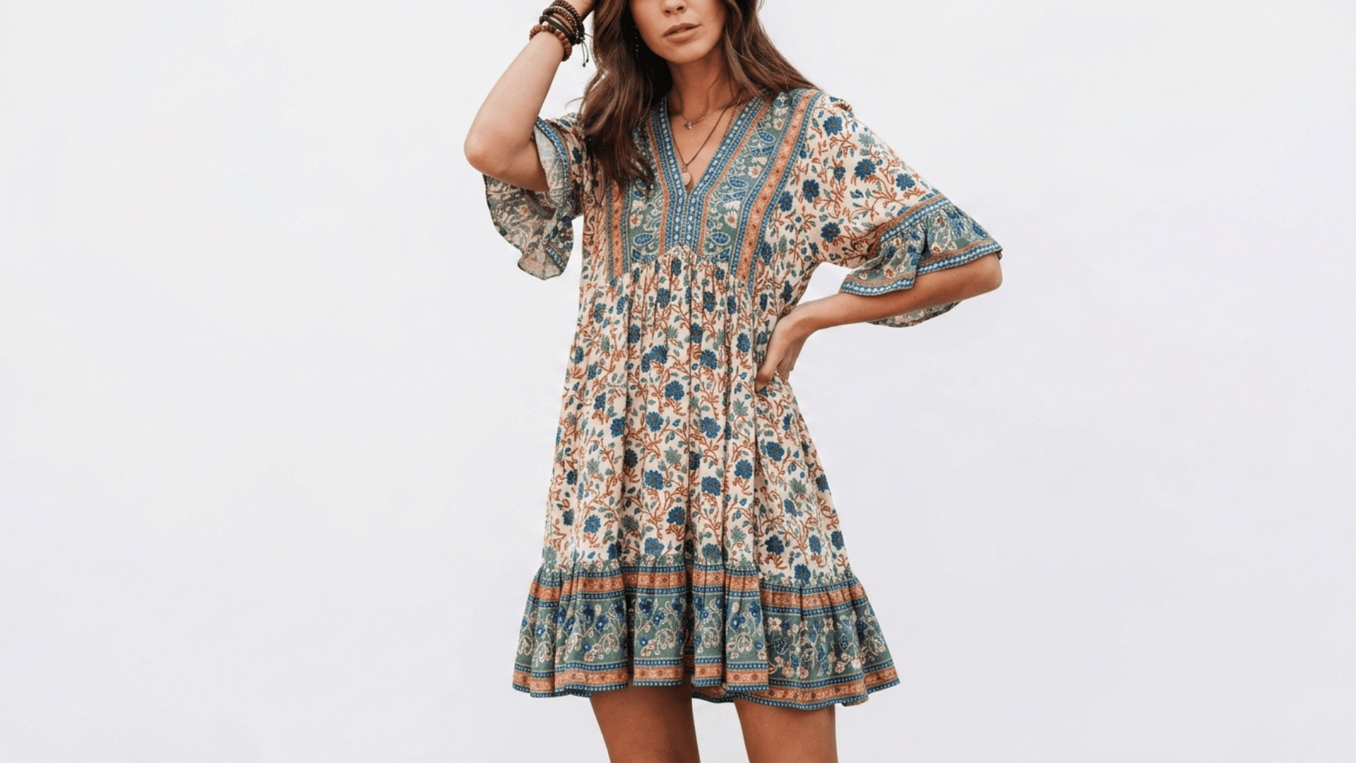 Woman wearing a vintage boho floral mini dress with ruffled sleeves and trim against a plain white background