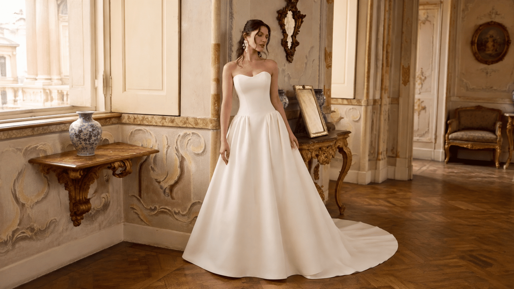 Woman wearing a white A-line dress with a fitted bodice and flared skirt in an elegant indoor setting.