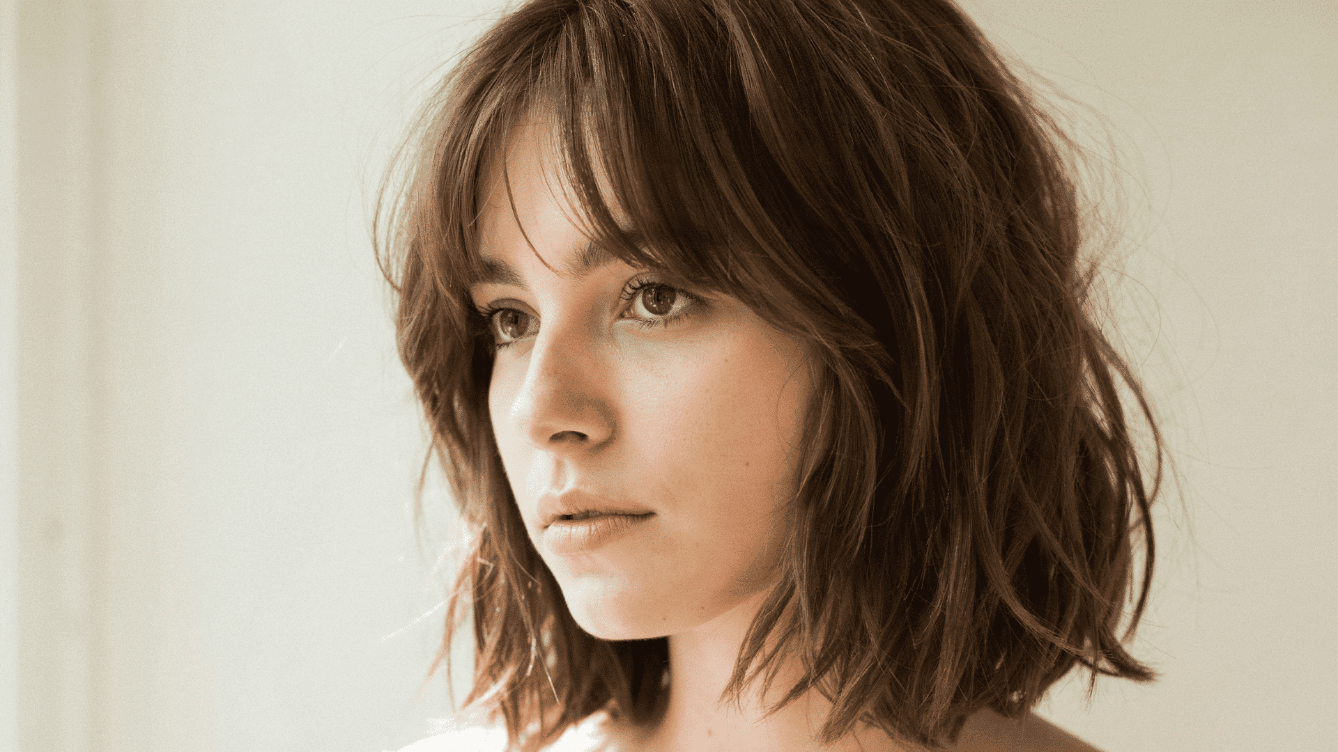 Woman with a soft layered medium haircut featuring shoulder-length waves and blended layers for natural movement and volume.