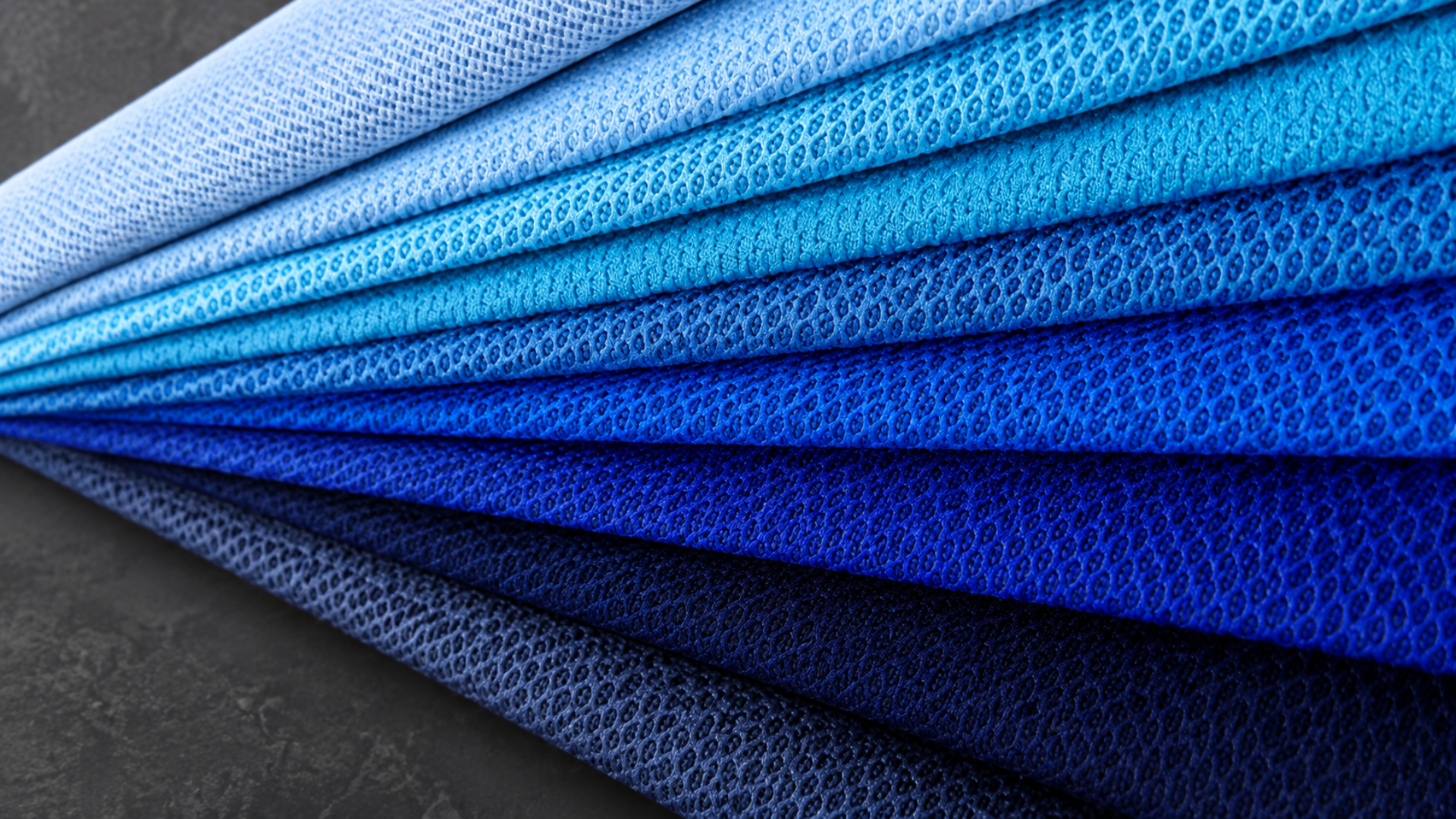 Layered blue polyamide fabric swatches showing mesh texture in multiple shades on a dark background
