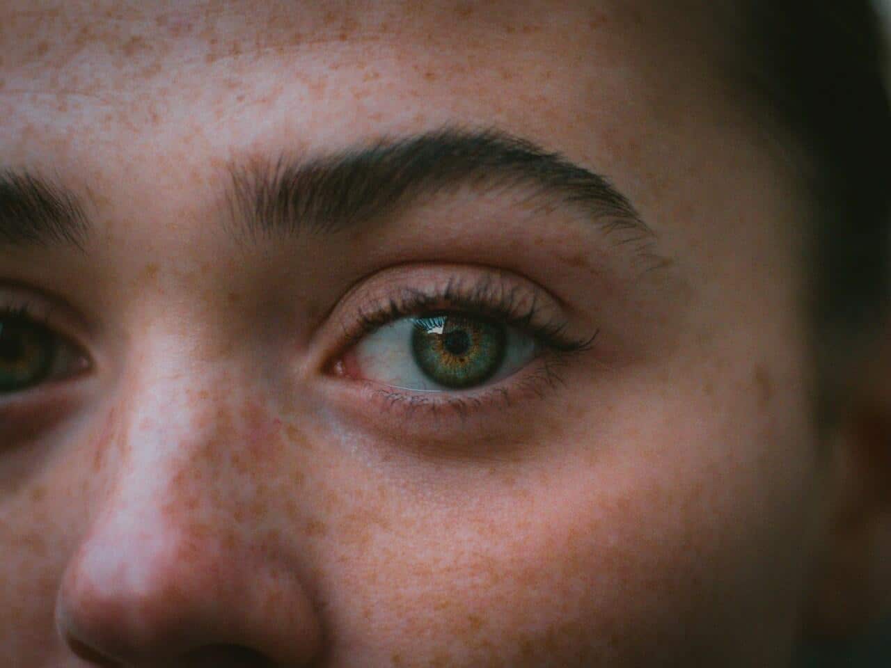 Close-up of person’s eye with freckles and natural skin tone