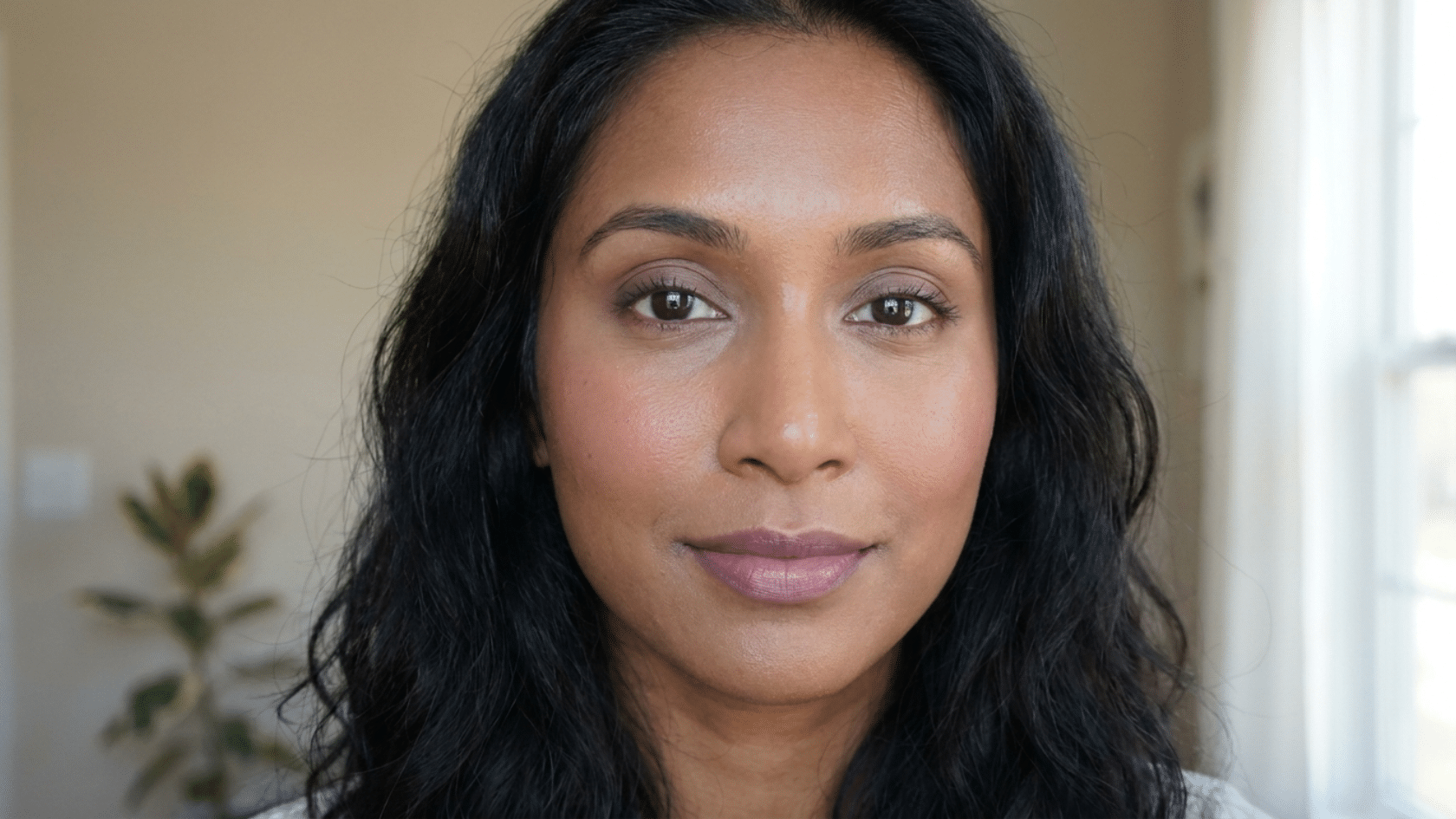 Soft summer makeup portrait of woman with natural blush, soft mauve lips, and minimal eye makeup in soft indoor lighting