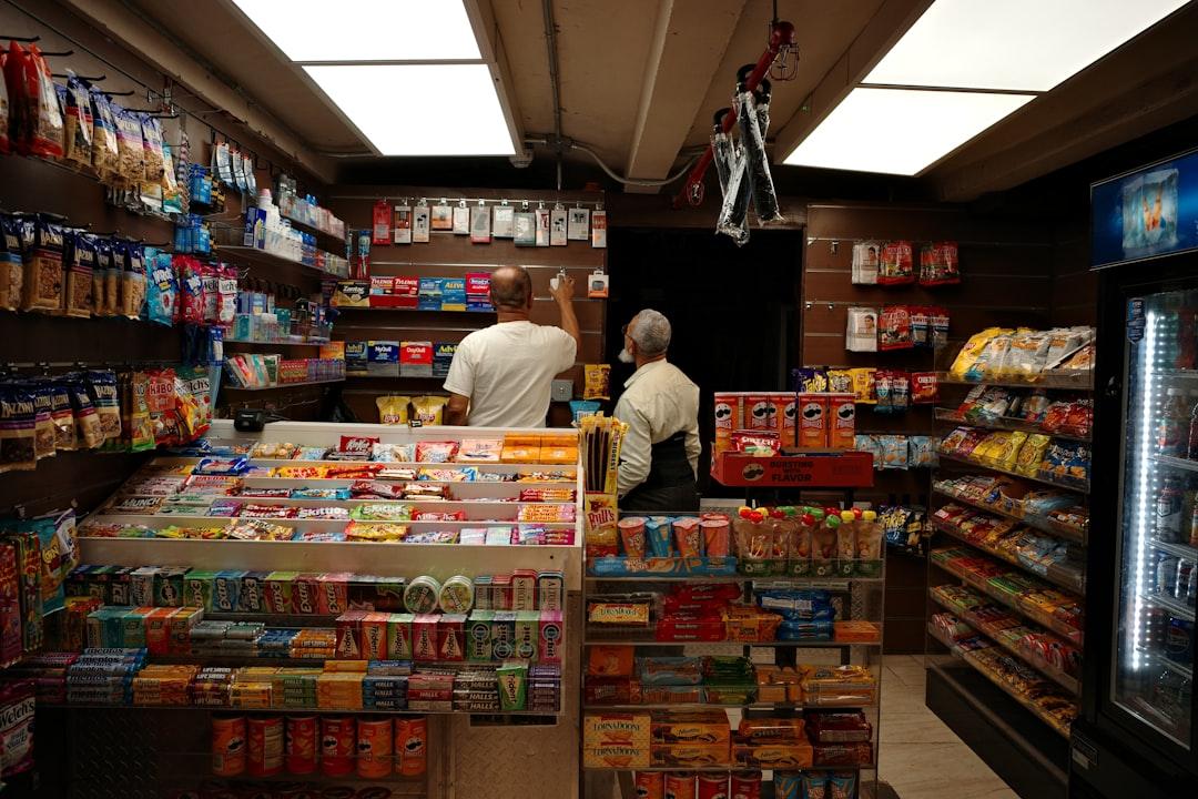 Small convenience store with two people browsing shelves filled with snacks and candies