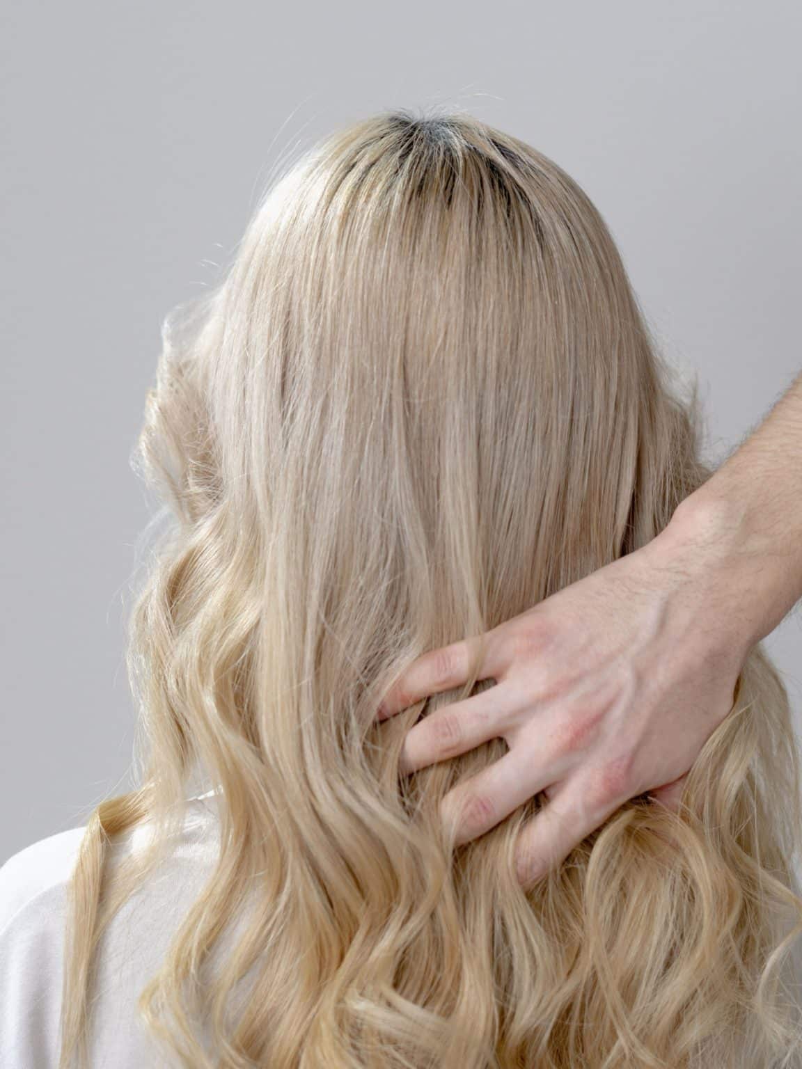 Hand tousling long wavy blonde hair in indoor setting