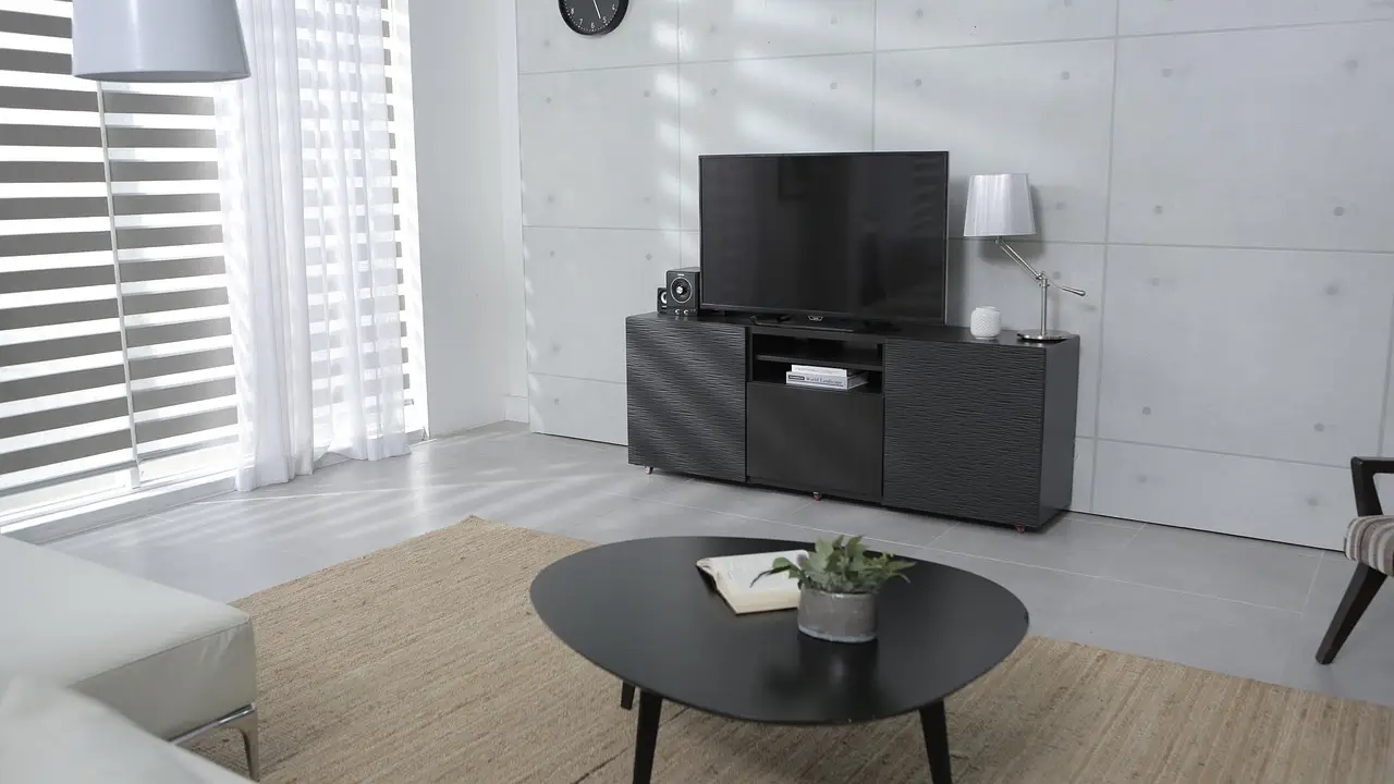 Modern living room with black TV unit, round table, and sheer curtains in bright natural light