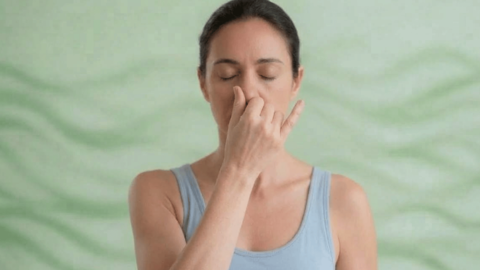 Person practicing alternate nostril breathing meditation with eyes closed.