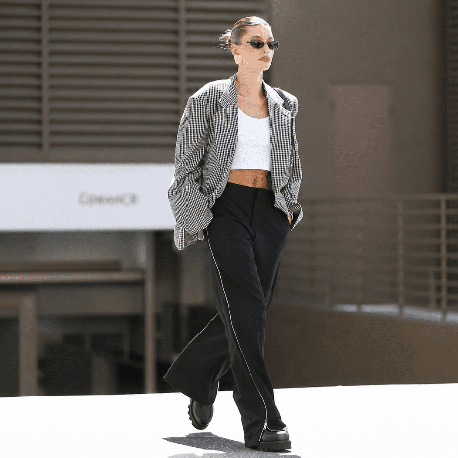 Hailey Bieber in an oversized checkered blazer and wide-leg pants, showcasing structured retro fashion trends.