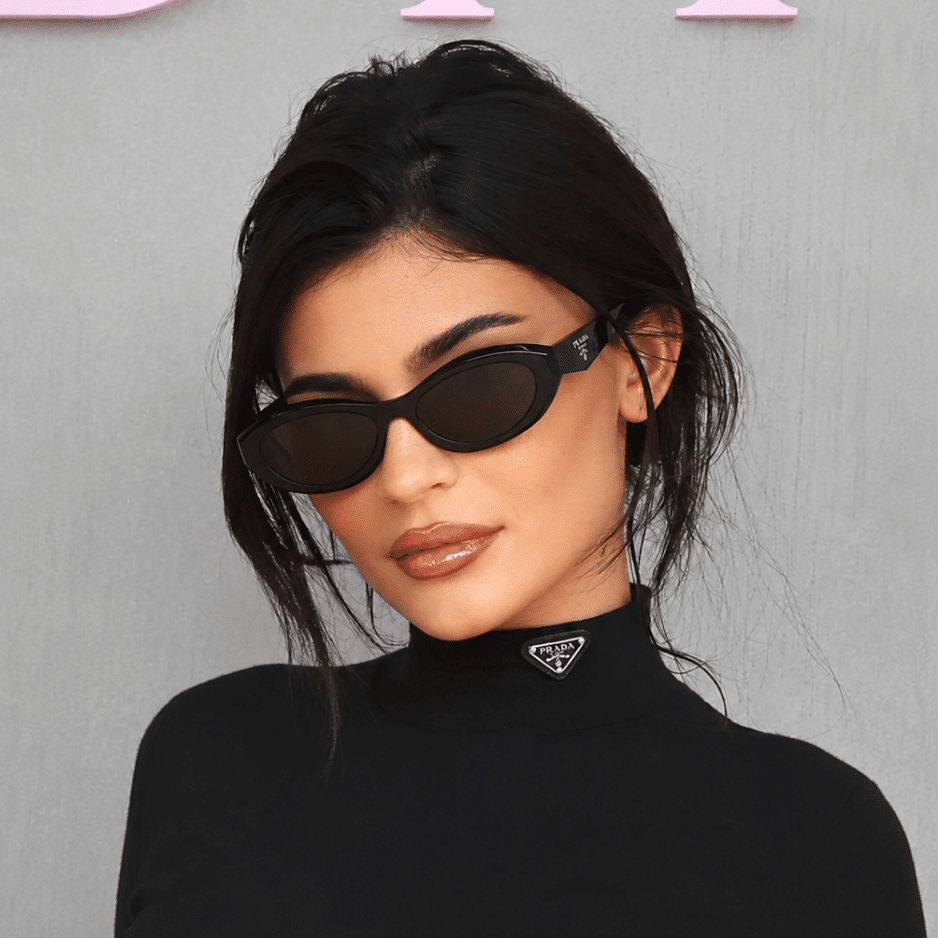 Kylie Jenner wearing bold black oval sunglasses and a high-neck top, reflecting sleek retro fashion trends.