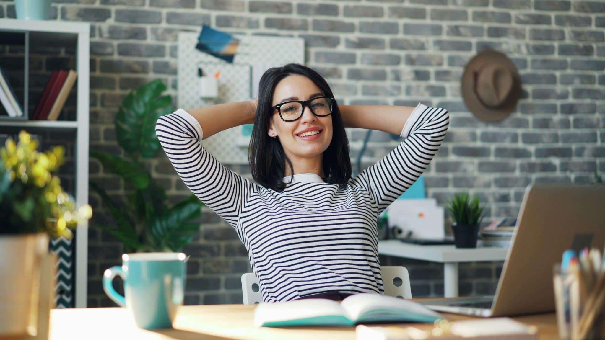 Person in striped shirt relaxing at desk in modern office with exposed brick wall
