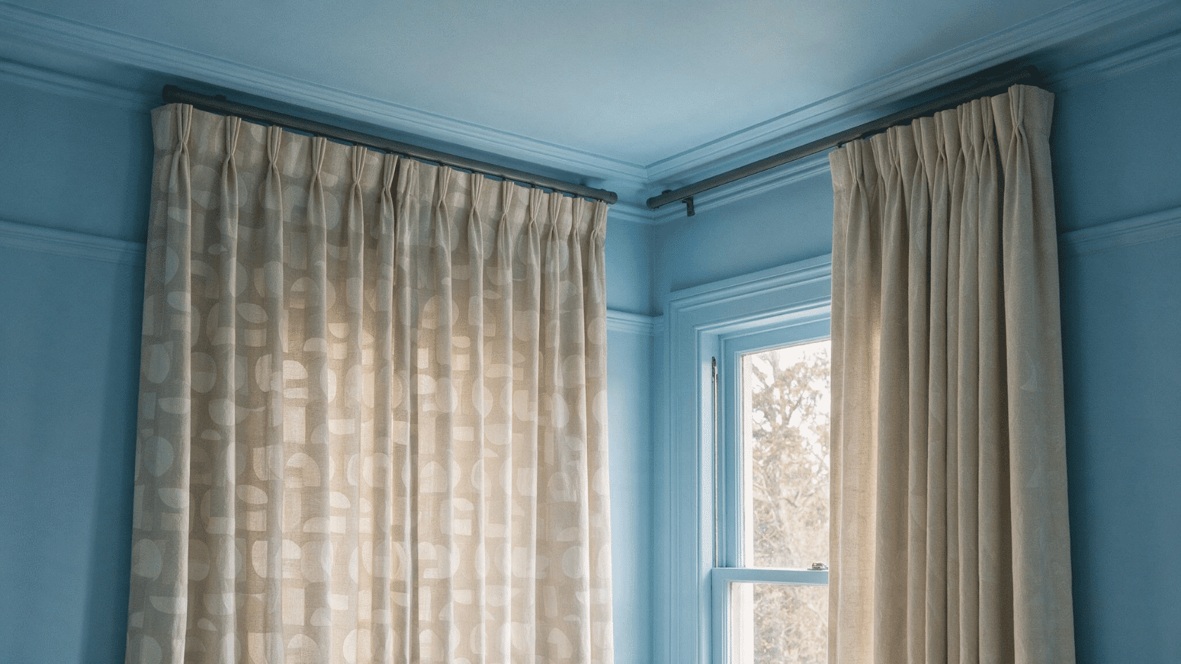 Ceiling-mounted hooks hold curtain rods for a clean straight-drop window treatment.