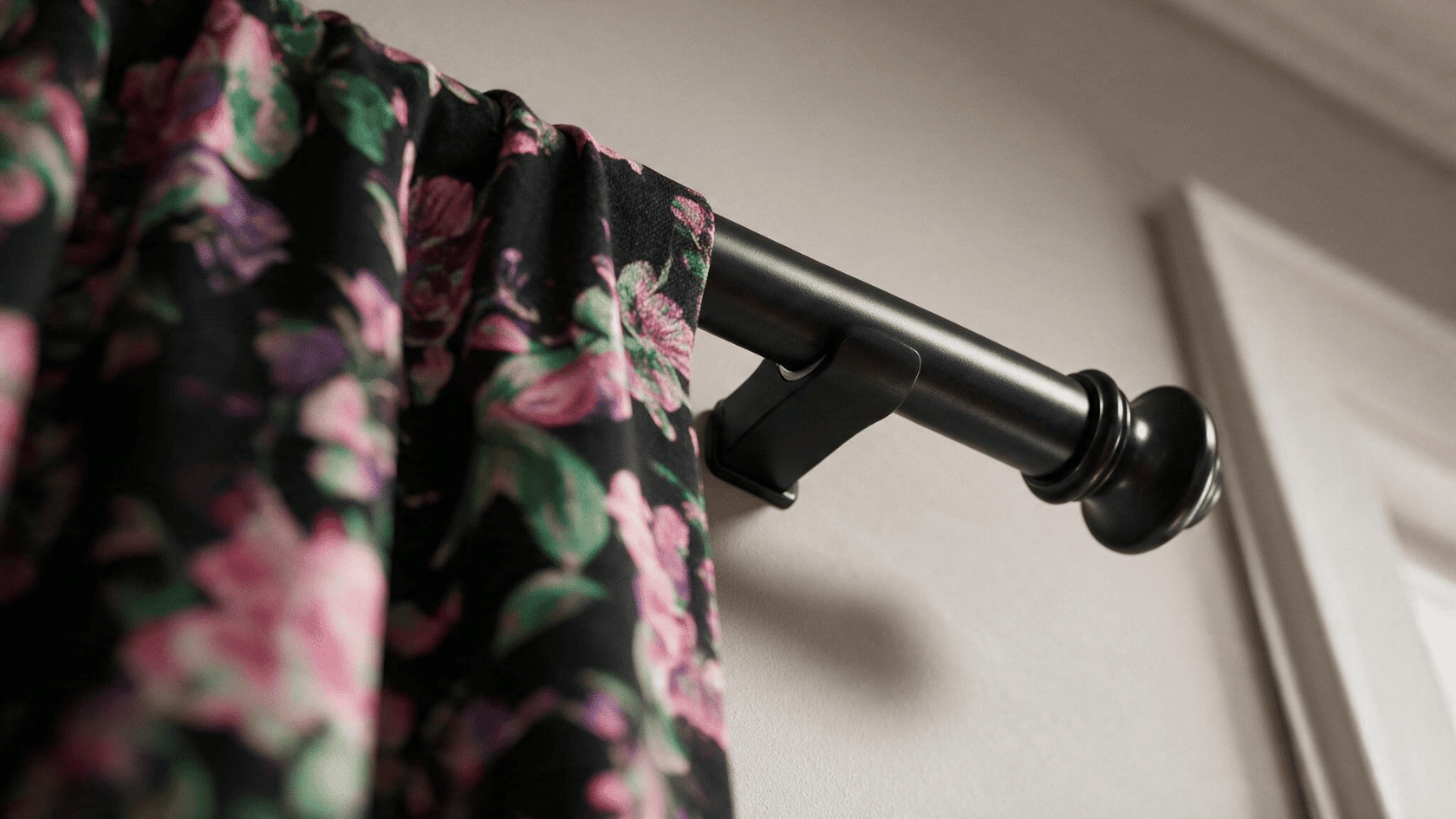 Floral curtain hanging from a magnetic curtain rod mounted near the window frame.