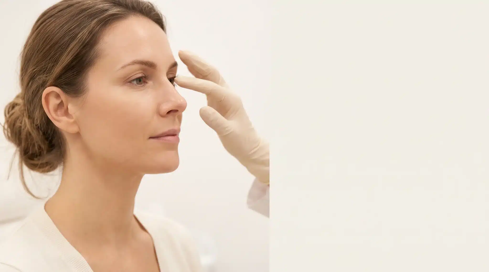 Dermatologist examining woman's nose in a bright clinical setting