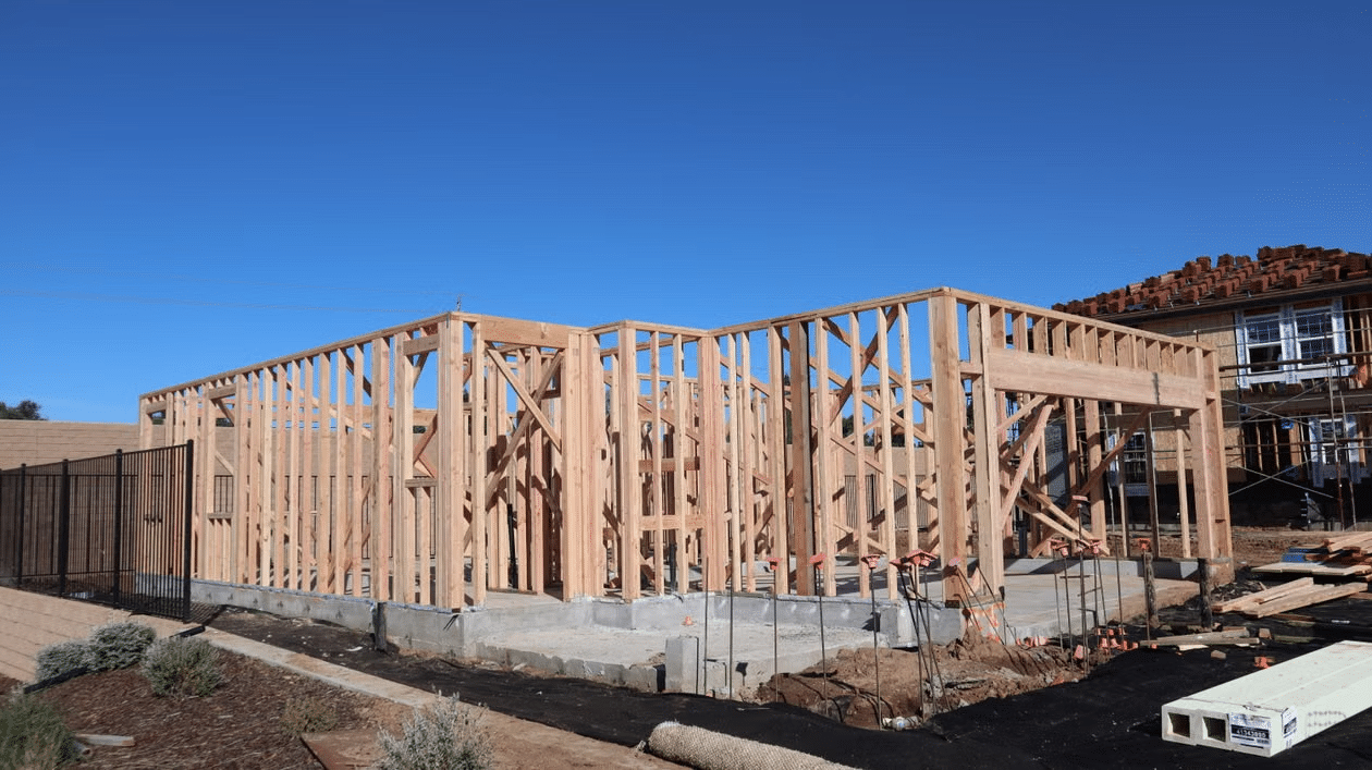 Wooden frame of a house under construction on a sunny day with clear blue sky