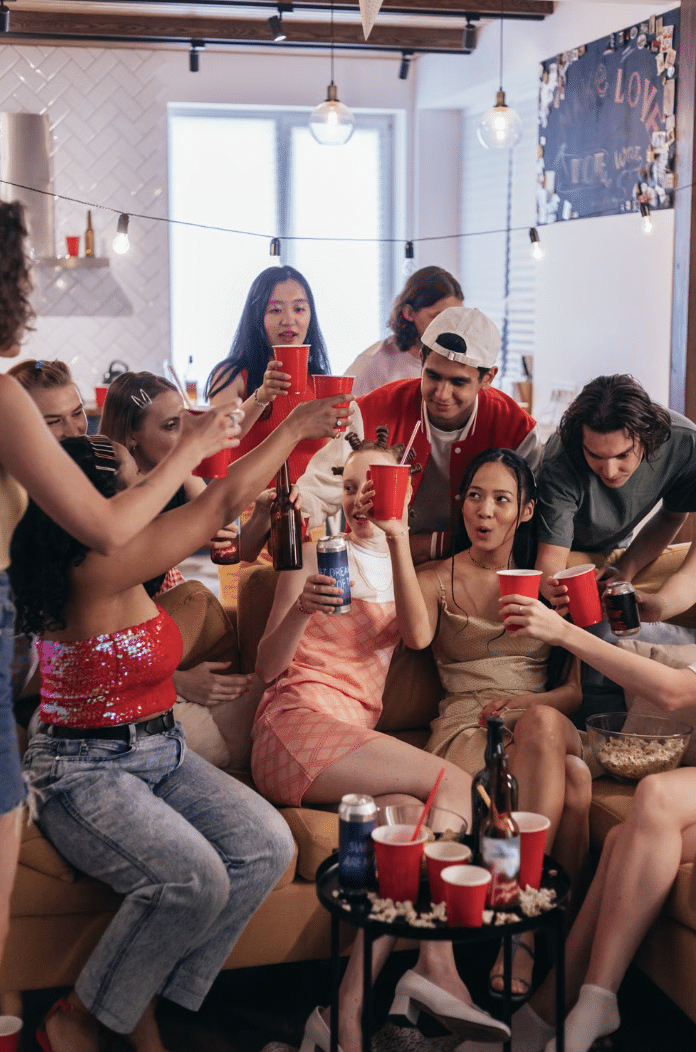 Group of friends cheering with red cups at a lively indoor party