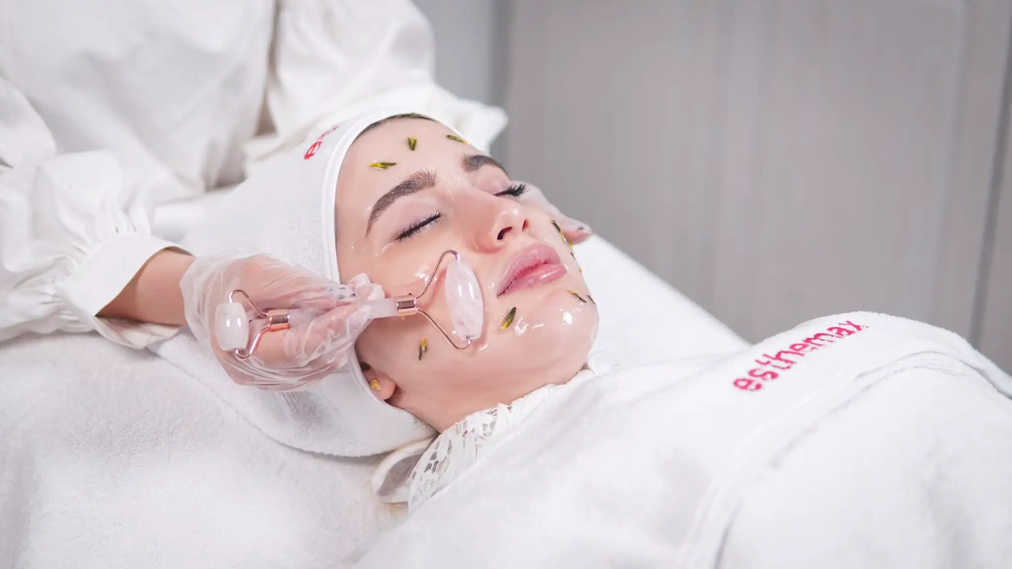 Person receiving facial treatment with jade roller in spa setting