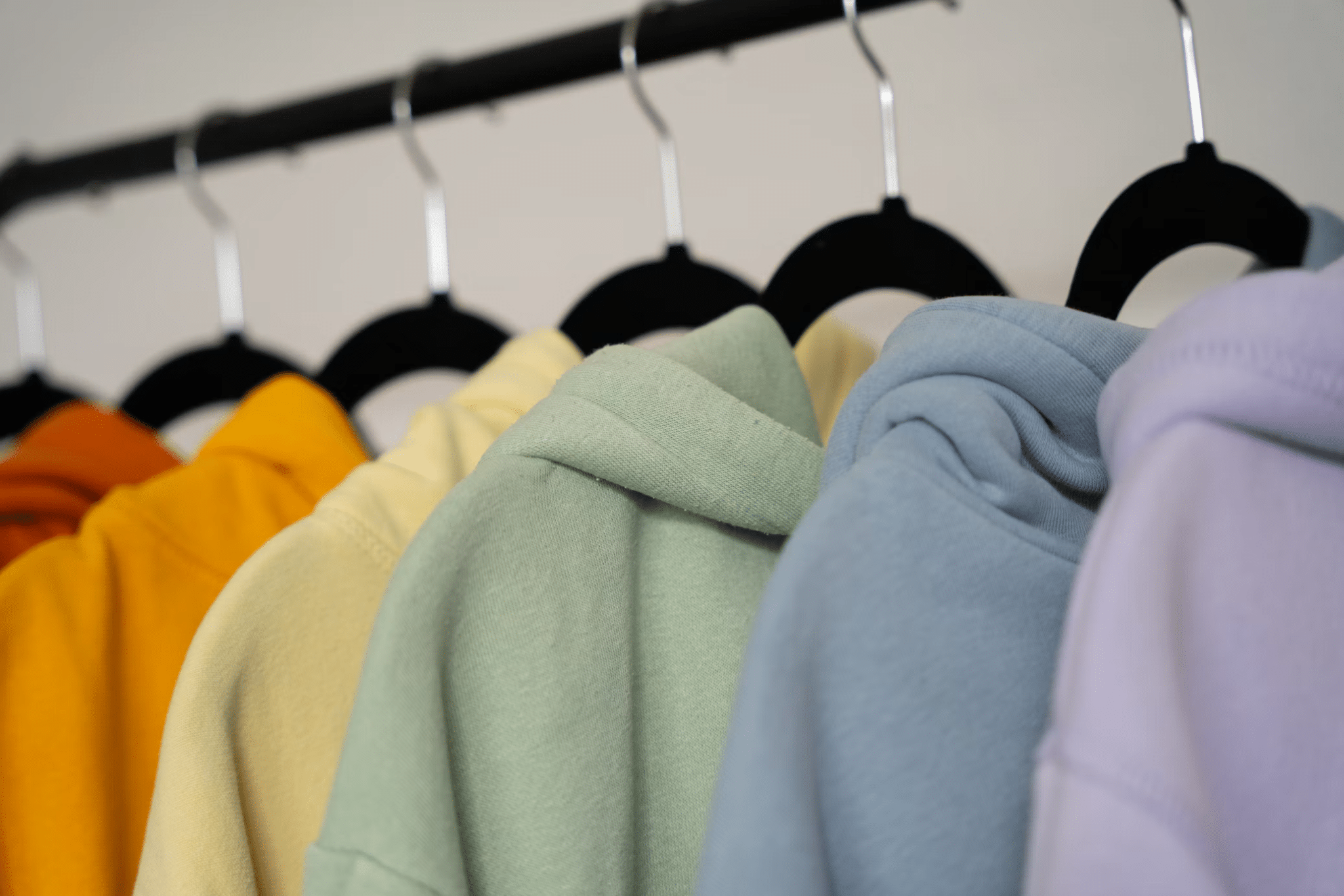 Colorful hoodies on black hangers in a close-up display indoor setting
