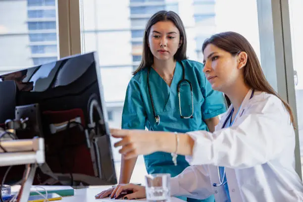 Two healthcare professionals reviewing information on computer screen in bright office setting