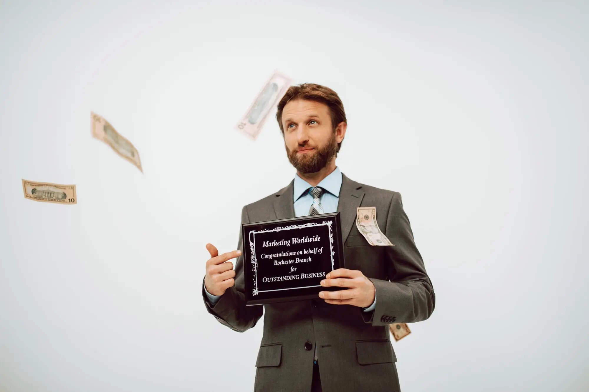 Man in suit holding business award with money floating in air