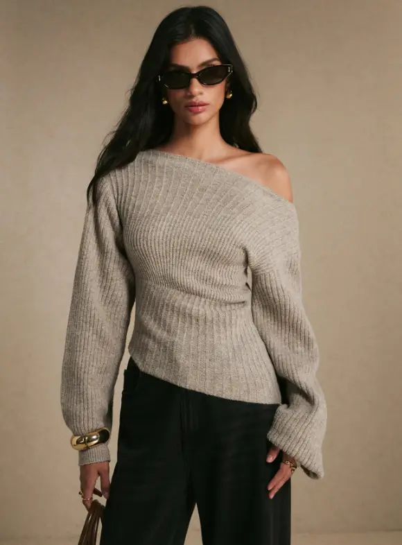 Model wearing an off-shoulder ribbed sweater, dark pants, and sunglasses in a neutral setting